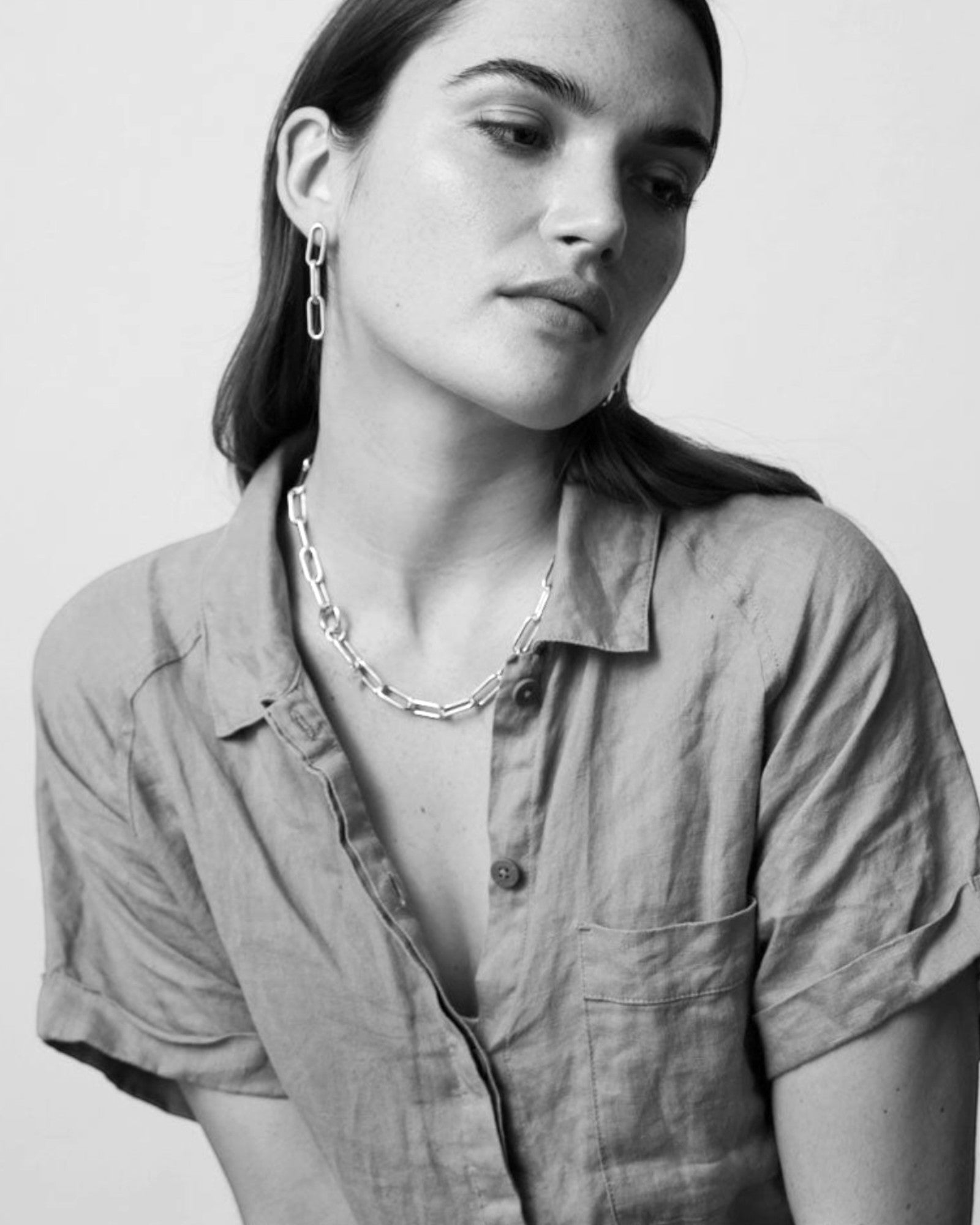 Molokai Quinn necklace featuring a bold silver chain link design worn by a woman in a casual linen shirt