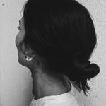 Molokai Zora twisted silver hoop earring worn by a woman with hair in a bun, side profile view